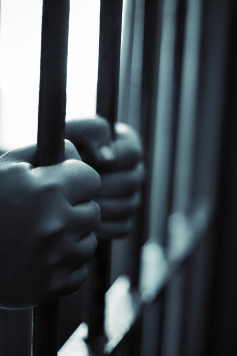 hands grasping prison bars