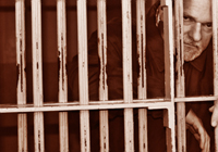 man scowling behind bars