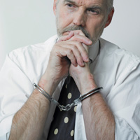 person in dress shirt and polka-dot tie wearing handcuffs