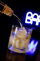 alcohol being poured into a glass full of ice