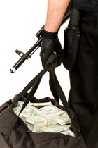 person wearing gloves holding bag of money and assault rifle
