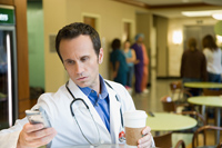 a doctor drinking coffee and looking at their phone