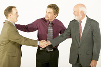 two people in suits shake hands with a third