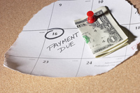a calendar with PAYMENT DUE written on it, money tacked next to it